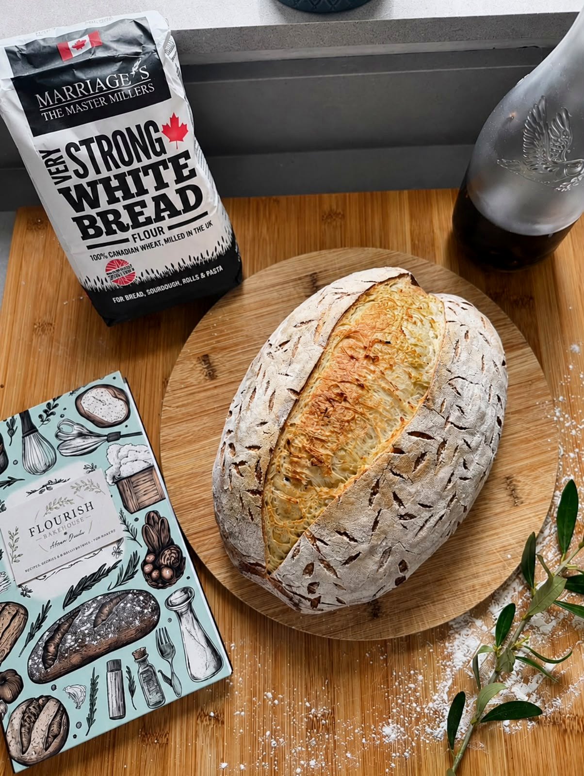 White sourdough loaf on a board with flour and packaging